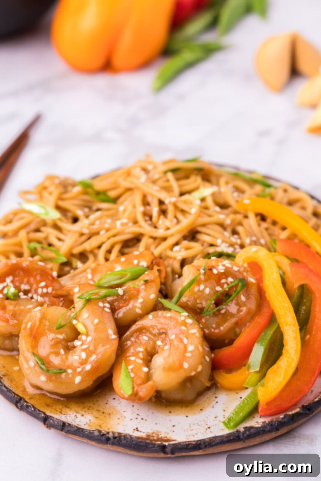 Teriyaki Shrimp served on a plate with homemade teriyaki noodles and fresh sliced bell peppers.