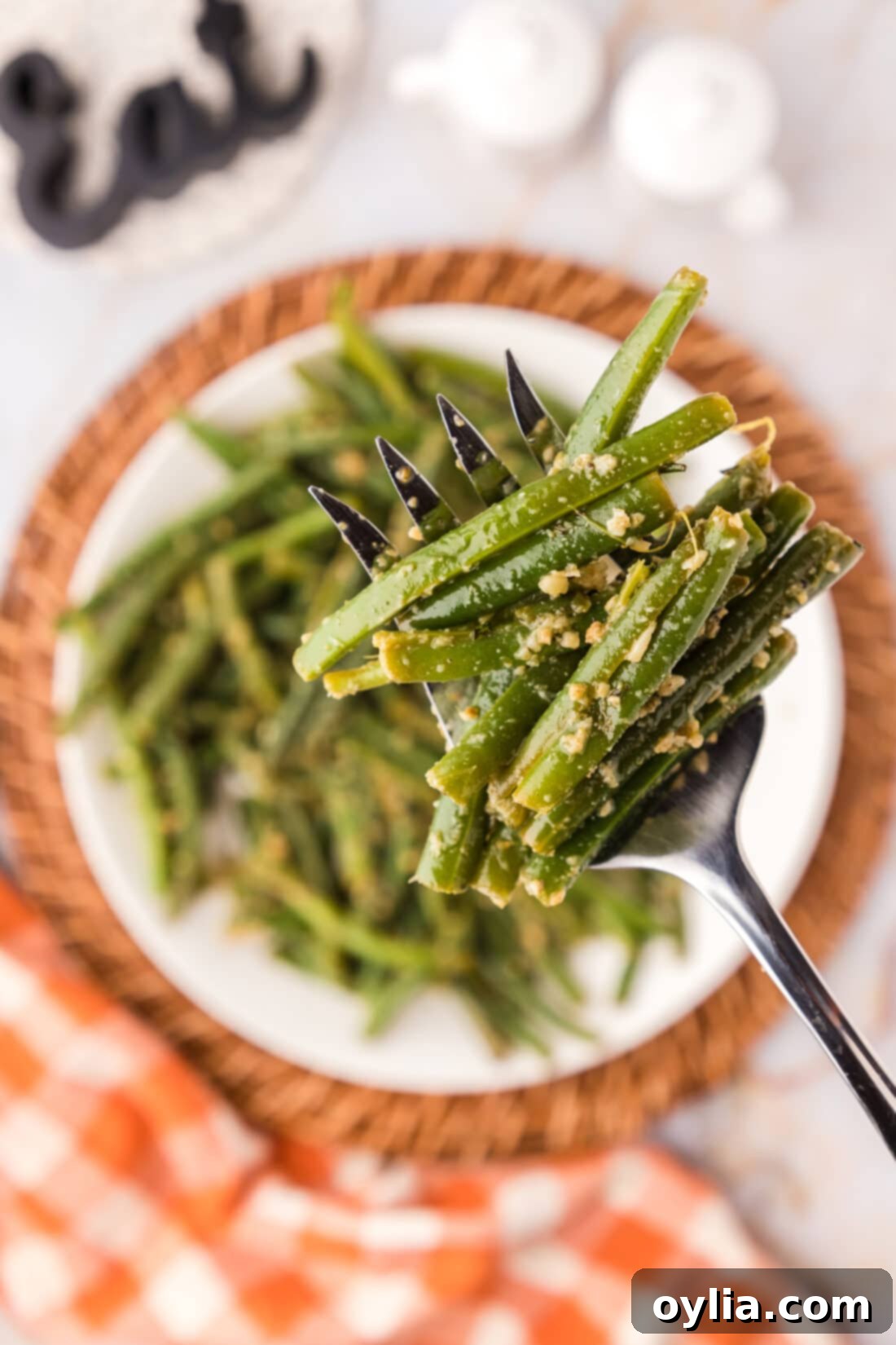 Garlic Green Beans on a fork held above a plate of Garlic Green Beans