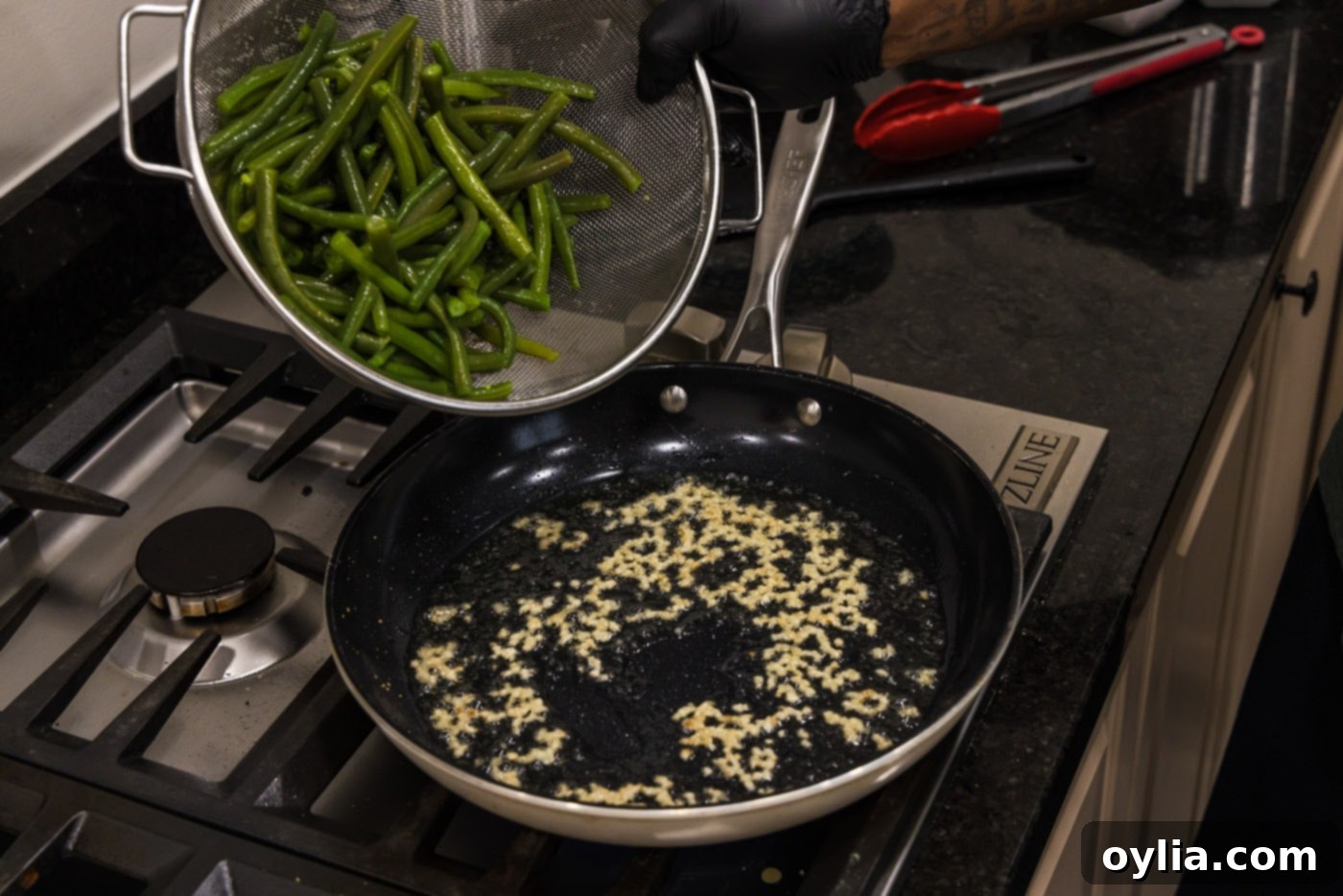 adding green beans to skillet with oil and garlic