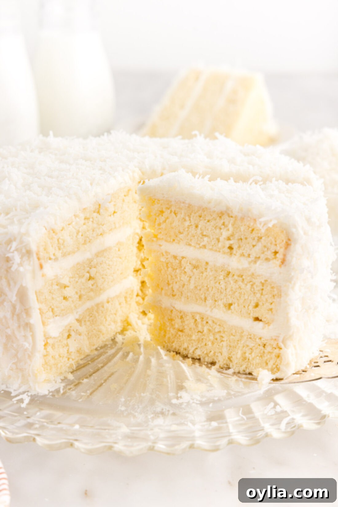 Coconut Cake 20 A glorious multi-layered coconut cake, beautifully frosted and covered in shredded coconut, with several slices already removed, showing off its inviting interior.