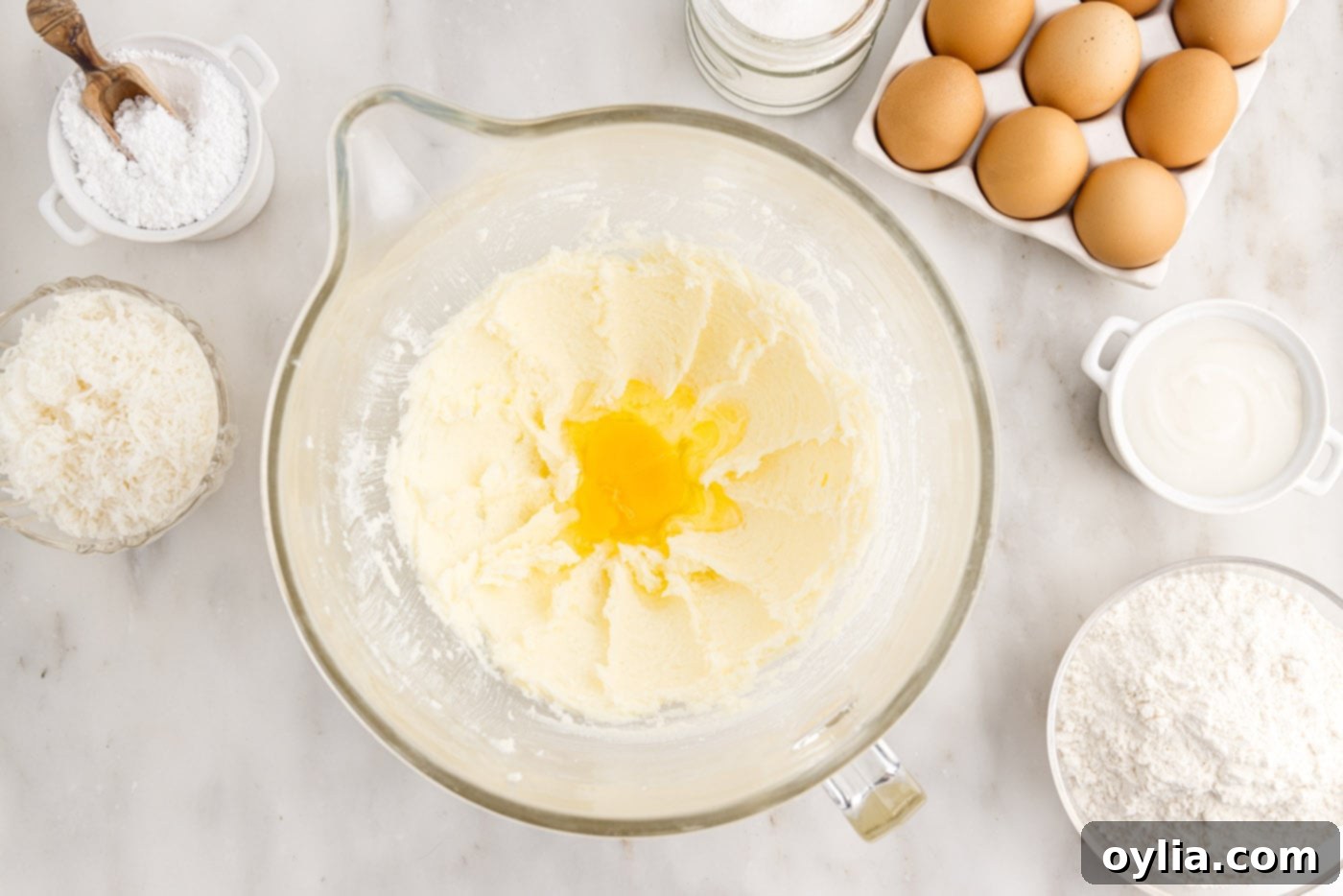 Three large eggs have been fully incorporated into the butter and sugar mixture, which now appears smooth and well-combined, ready for the next wet ingredients.