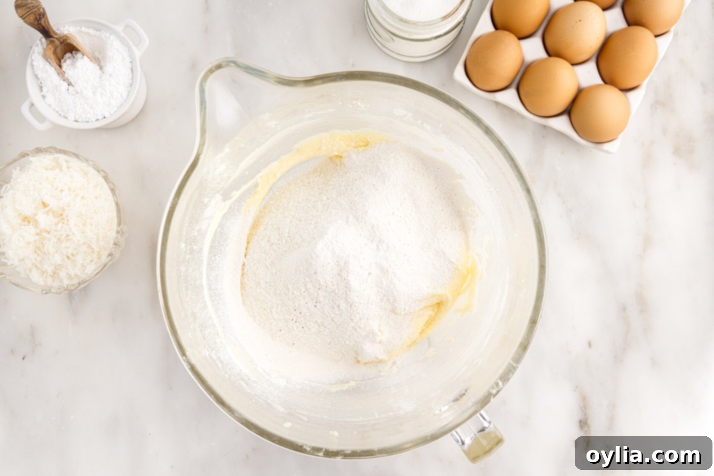 The dry ingredients, flour, baking powder, and salt, are being carefully added to the wet cake batter in stages, ready to be gently mixed.