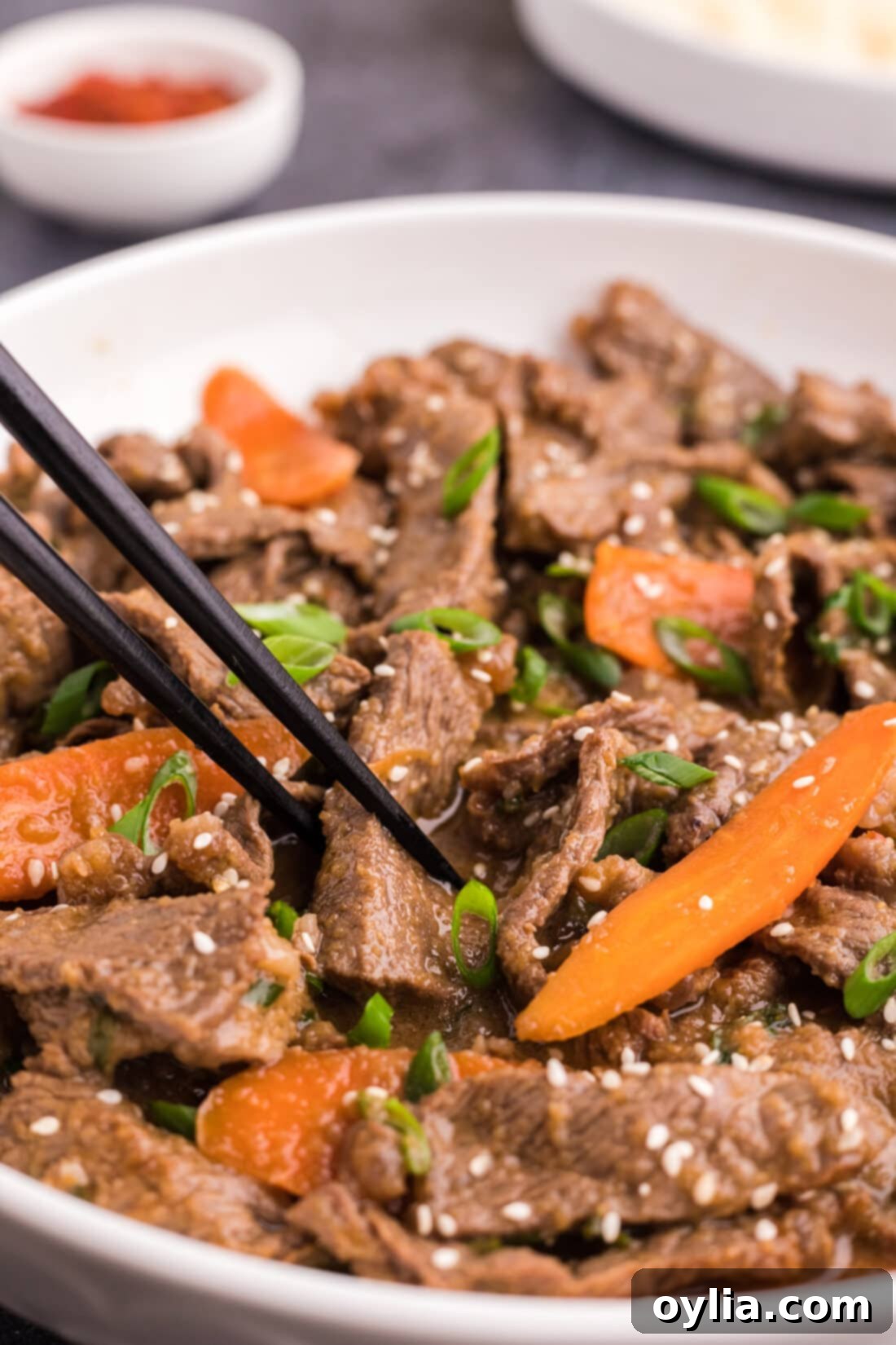 Sweet and Savory Korean BBQ Beef 2 A bowl of delicious Beef Bulgogi topped with sesame seeds and green onions, with chopsticks ready to serve.