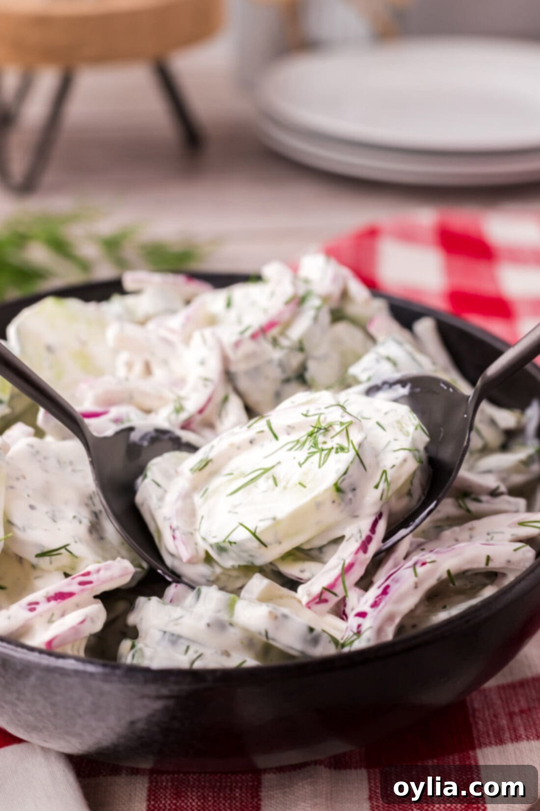 Two spoons in a bowl of Creamy Cucumber Salad