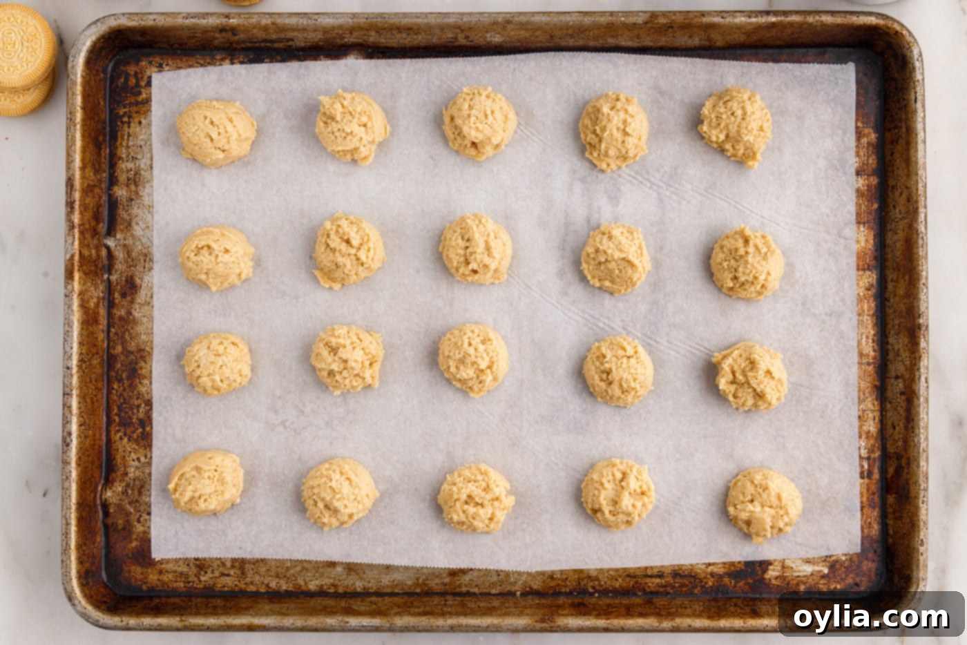 Golden Oreo truffle balls placed on a parchment-lined baking sheet before chilling