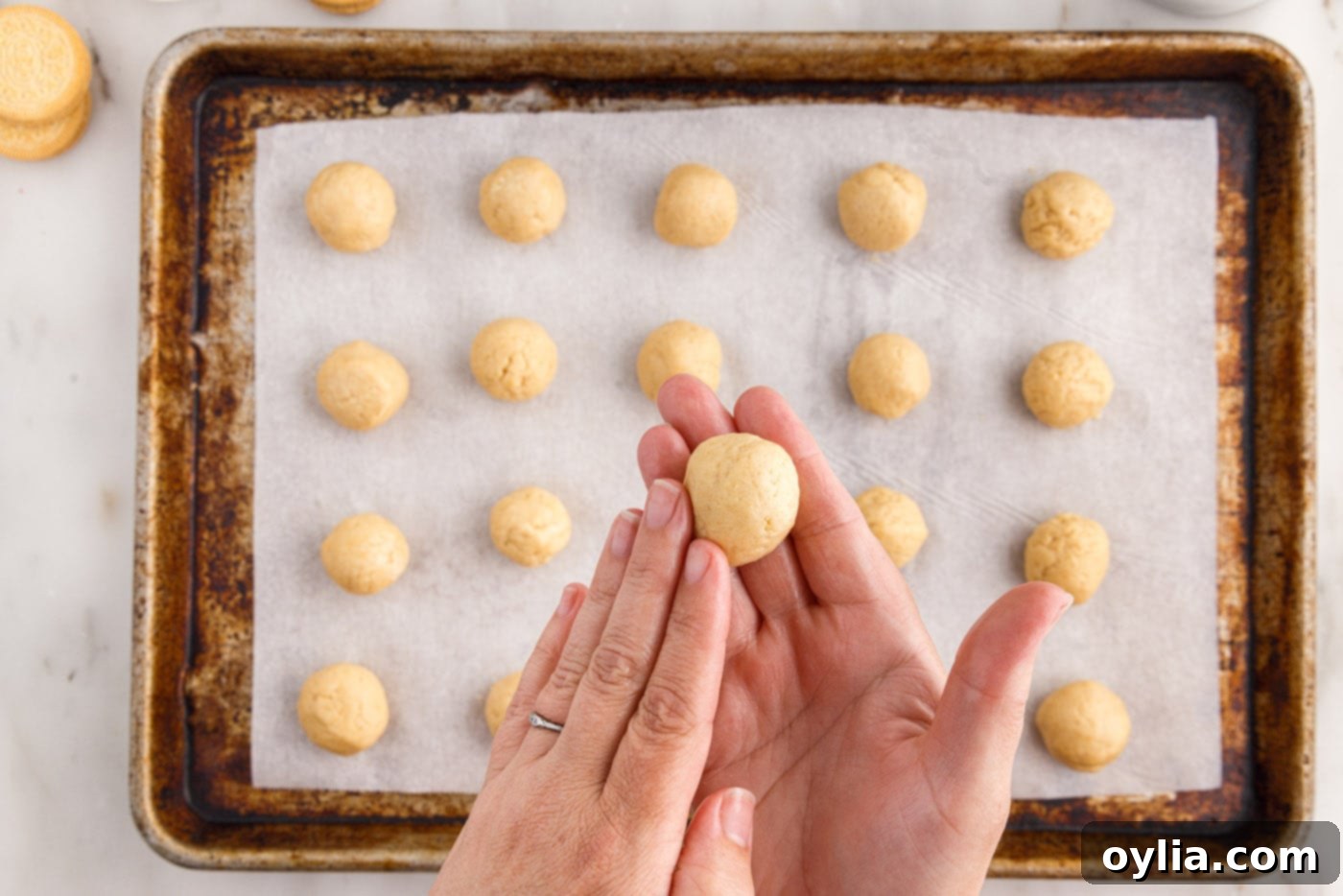 Hands rolling a Golden Oreo truffle ball to create a smooth, round shape
