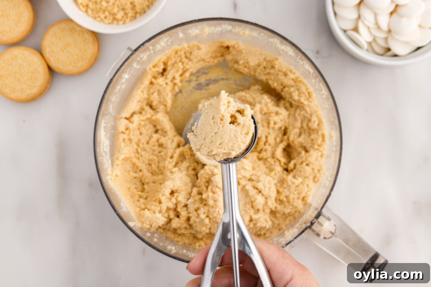 Scooping Golden Oreo truffle mixture from a bowl onto a baking sheet