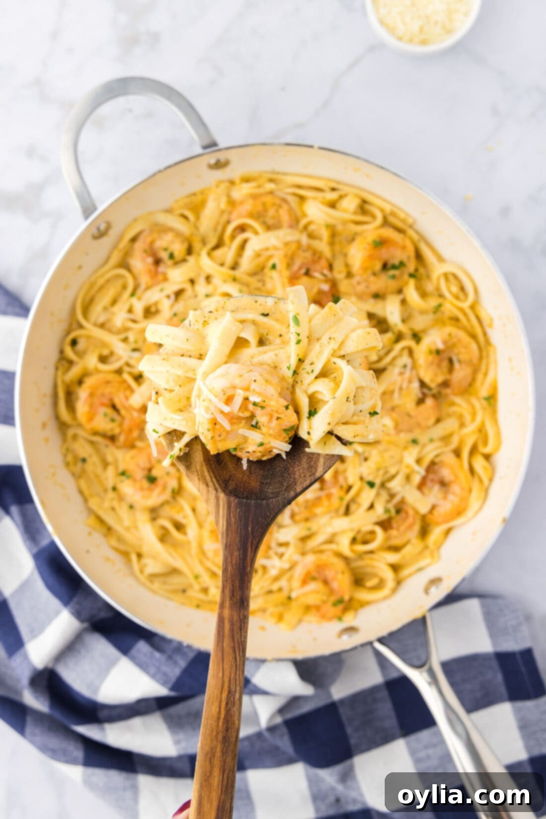 A spoonful of creamy shrimp alfredo pasta lifted from a skillet, showcasing the rich sauce and succulent shrimp