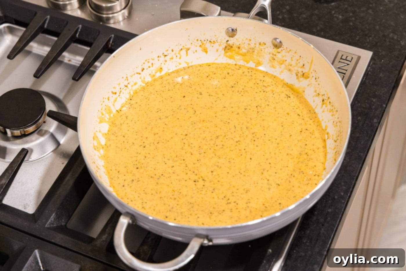 Rich and creamy homemade alfredo sauce simmering gently in a skillet, perfectly thickened