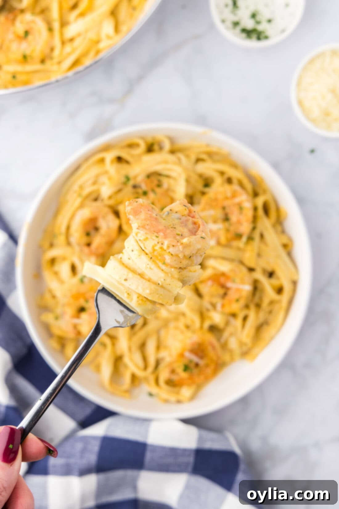 Fork twirling tender shrimp alfredo over a bowl, showcasing the creamy sauce and succulent shrimp