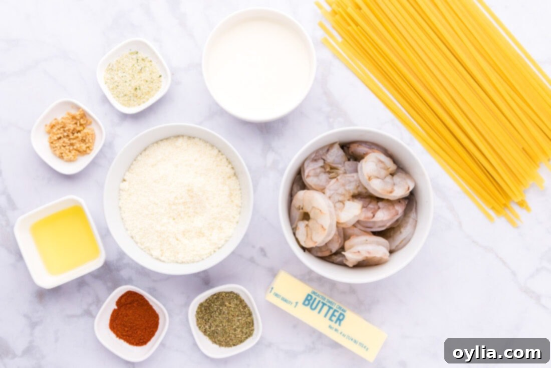 Various ingredients for shrimp alfredo arranged on a counter, including shrimp, pasta, cream, butter, and seasonings