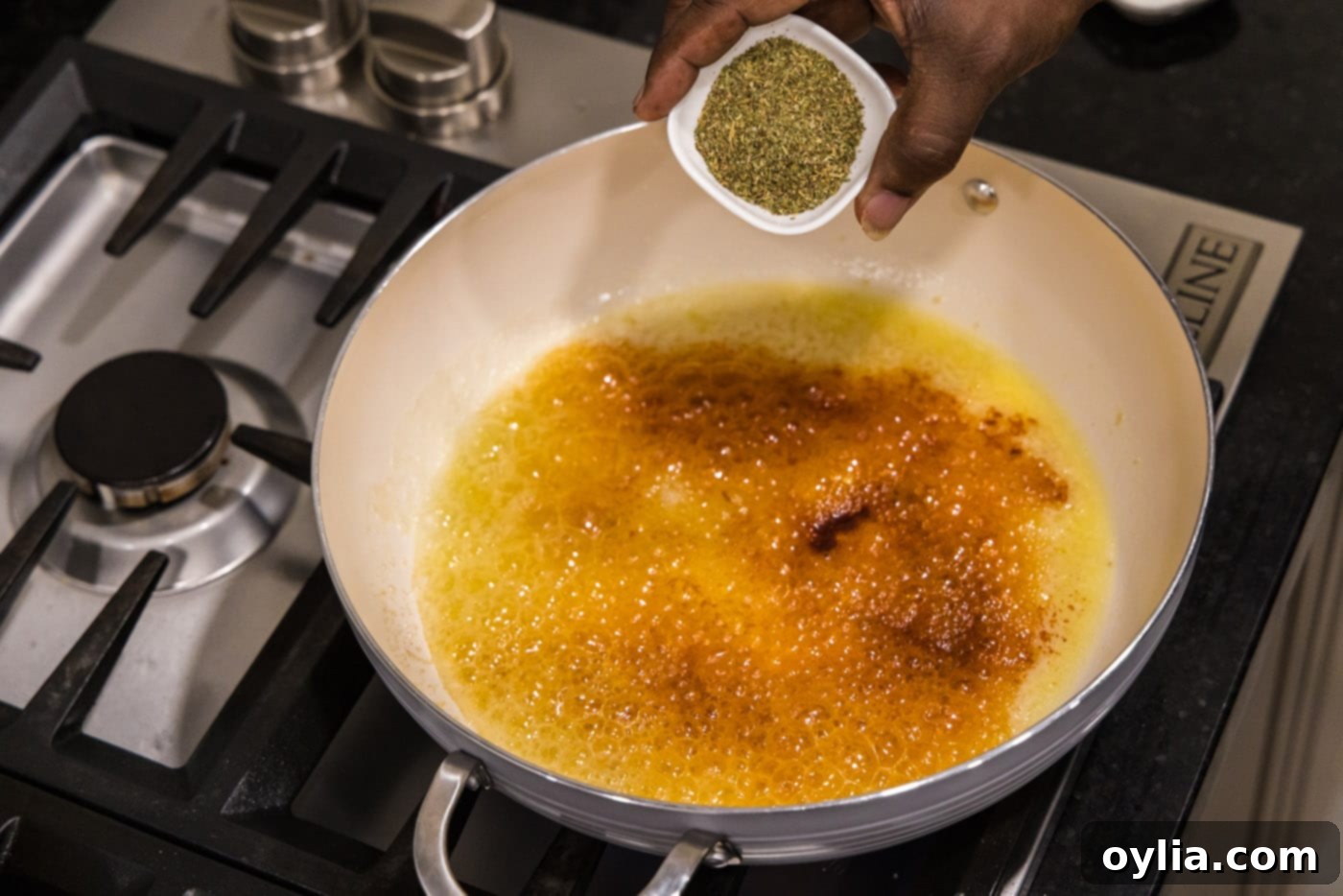 Minced garlic, paprika, and Italian seasoning being added to melted butter in a skillet for the alfredo sauce