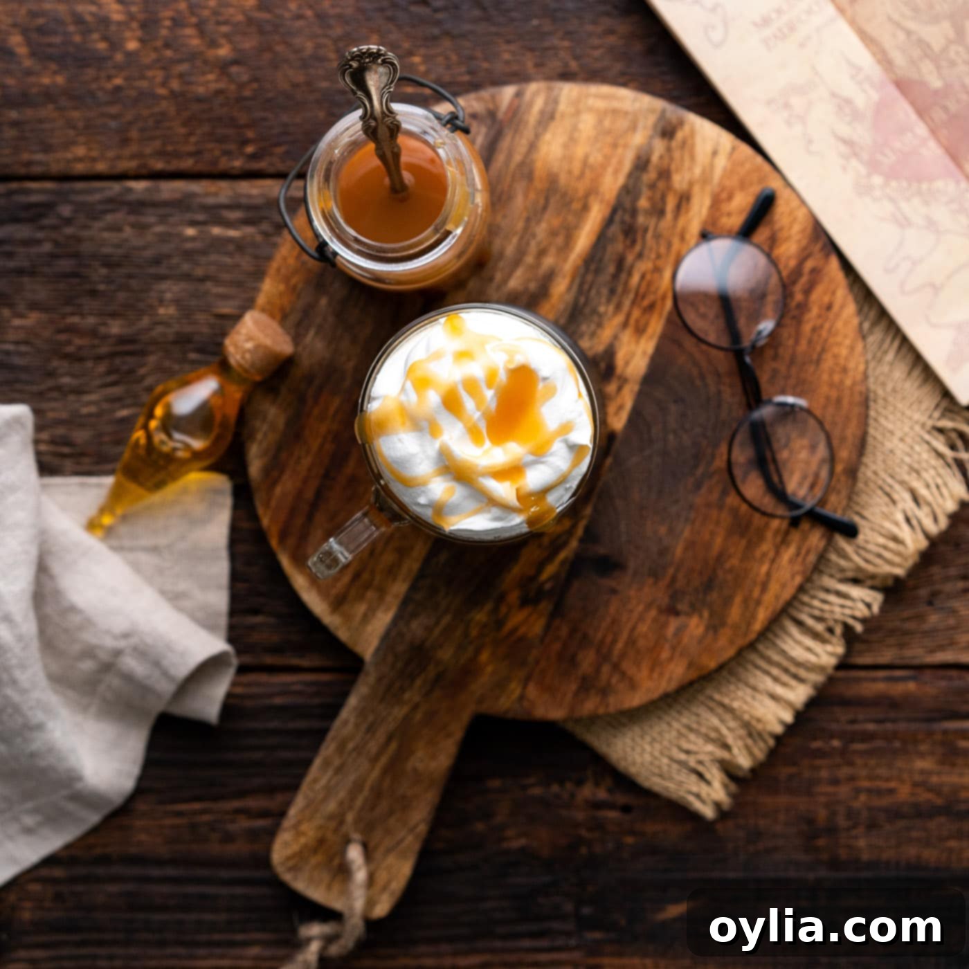 An overhead view capturing the perfectly finished Butterbeer, complete with frothy whipped cream and butterscotch drizzle, ready for serving.