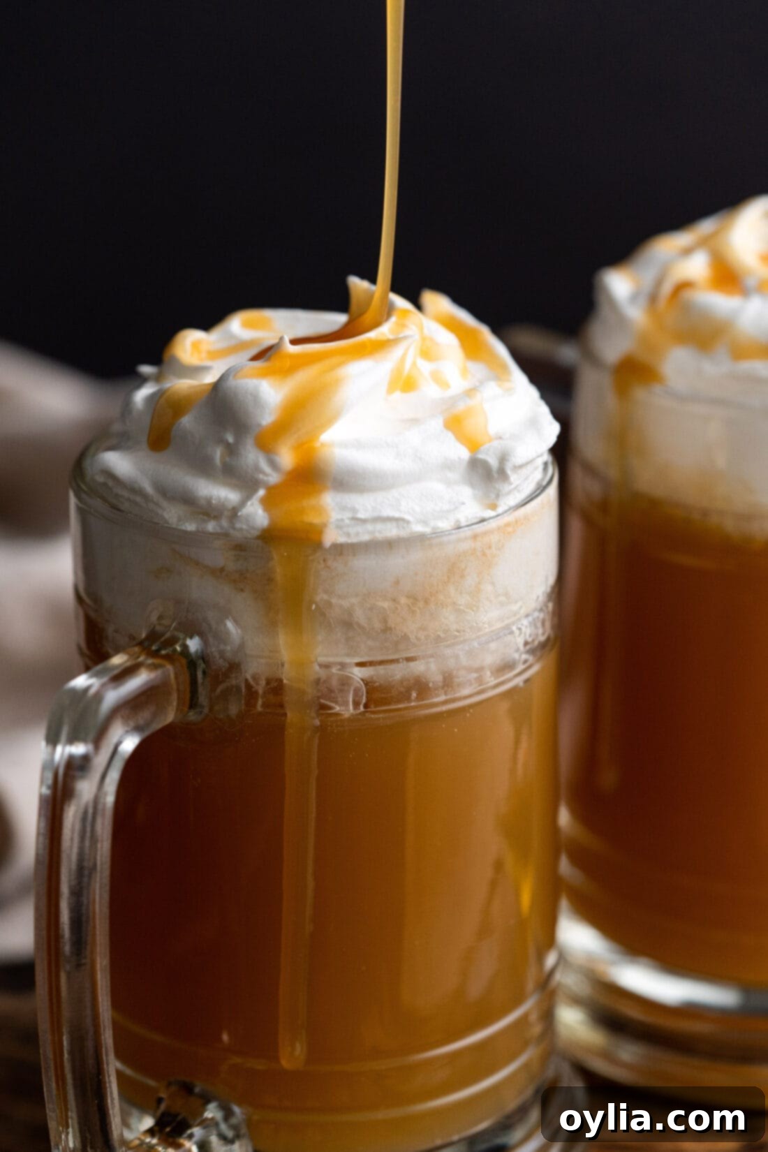 A close-up shot of butterscotch syrup being elegantly drizzled over a glass of Butterbeer, adding a final touch of sweetness.