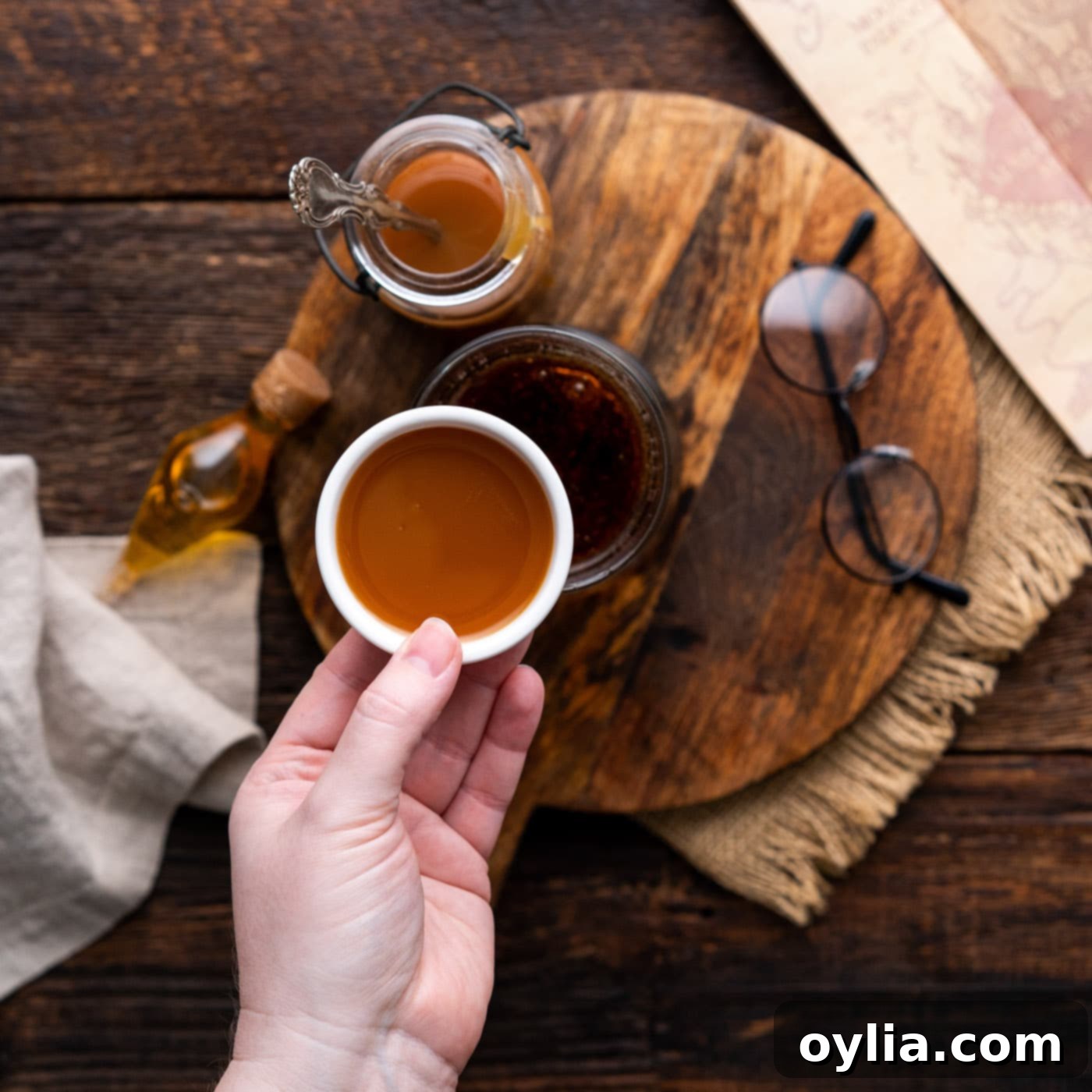A stream of rich butterscotch syrup being added to the cream soda in a mug, mixing the flavors for Butterbeer.