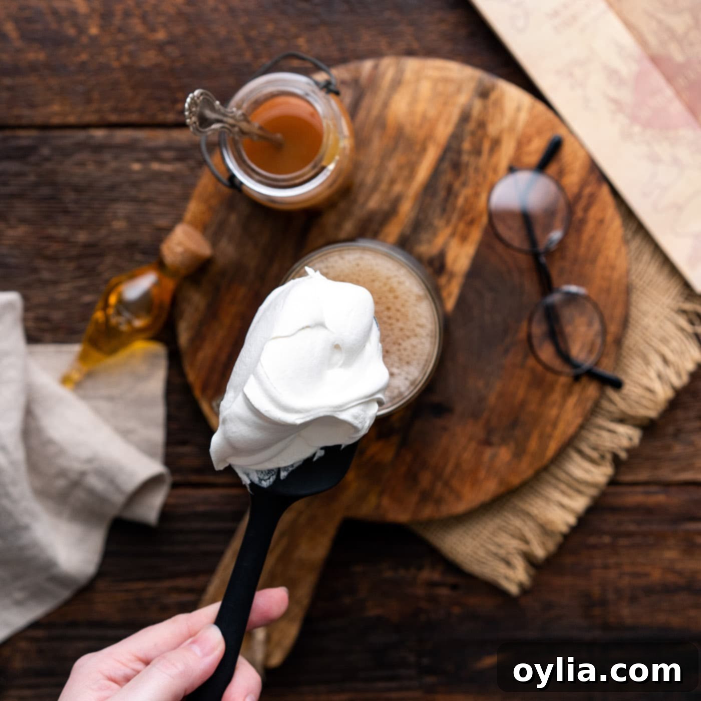 A large dollop of fluffy whipped cream elegantly placed on top of the Butterbeer in a mug.