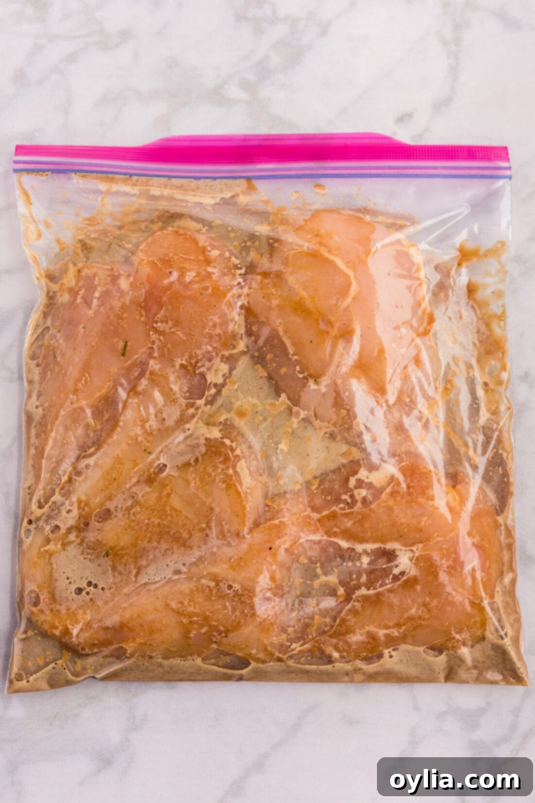 Chicken breasts marinating in honey garlic sauce inside a zip-top bag.