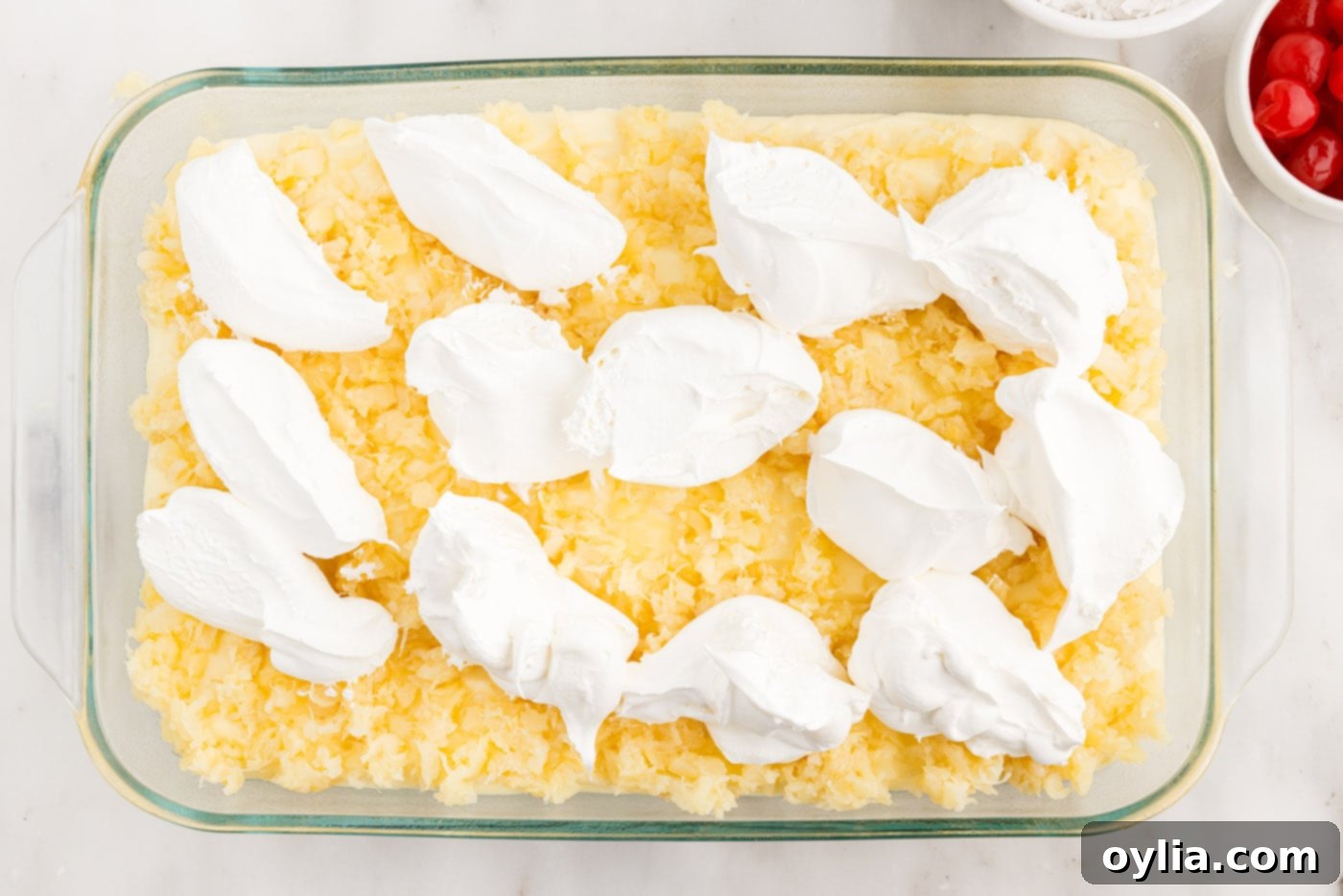 dollops of cool whip over crushed pineapple on cake