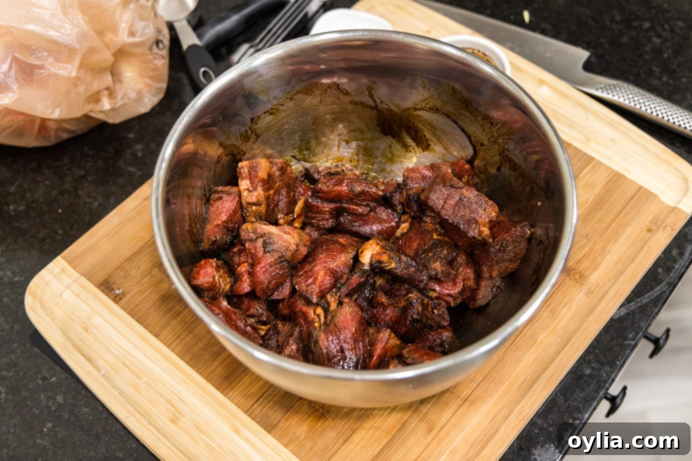beef tips coated in browning sauce and dry seasoning in a bowl, ready for searing