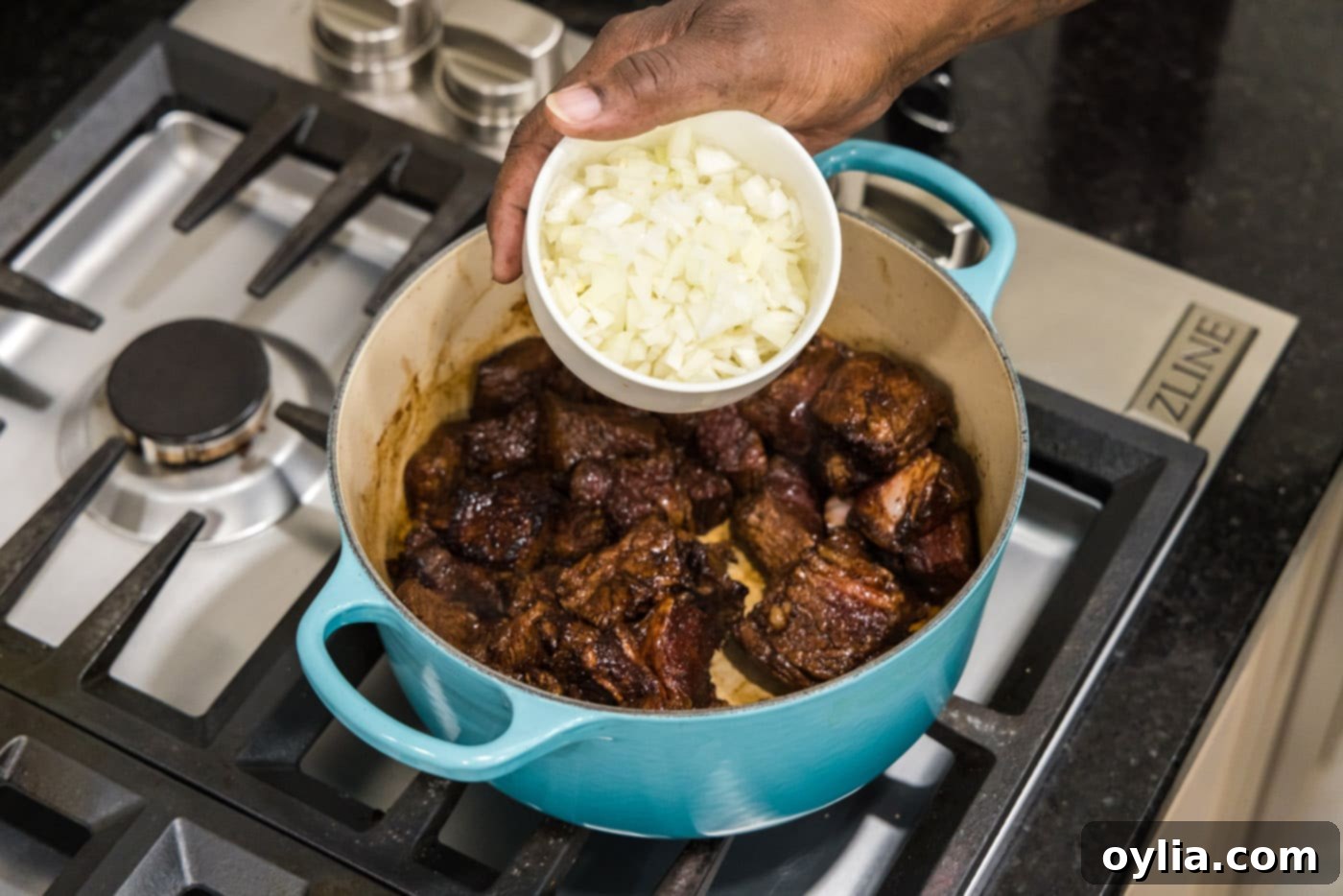 adding diced onion to dutch oven with browned beef tips
