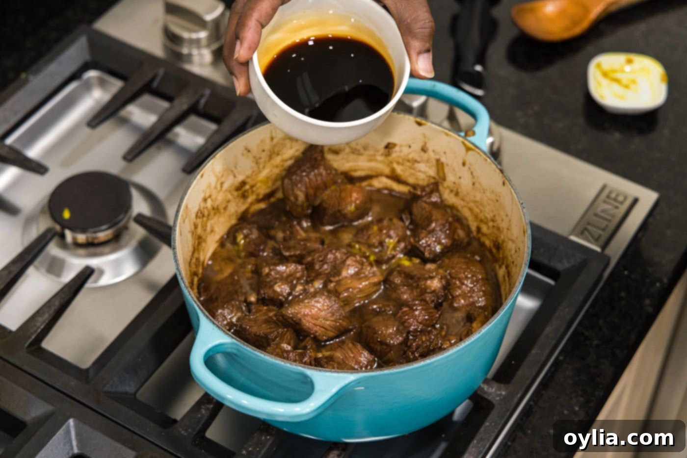 pouring soy sauce into pot with beef tips, adding depth of flavor