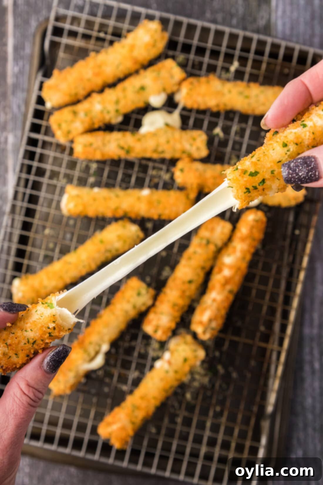 Wonton Cheese Stick cheese pull over a pan of Wonton Cheese Sticks