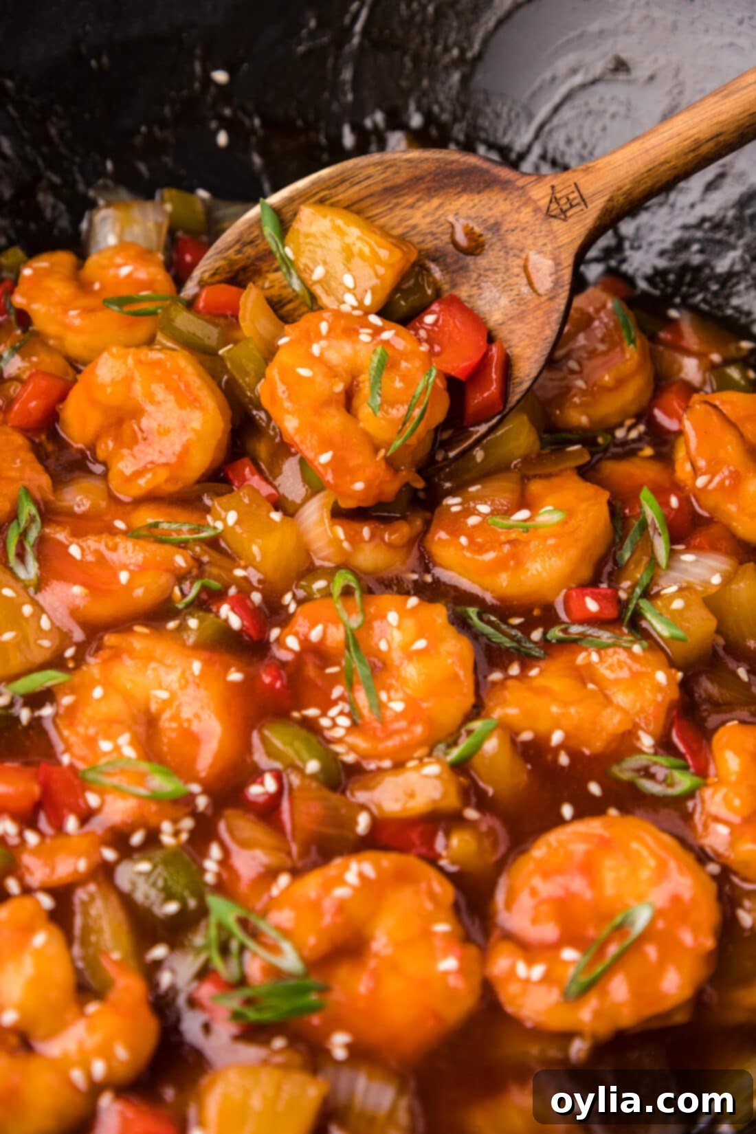 Close up photo of Sweet and Sour Shrimp in a wok with a spoon, highlighting crispy texture and vibrant sauce.