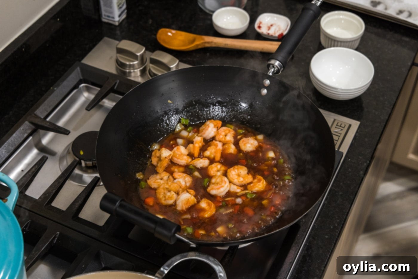 Cooked crispy shrimp added to the wok, simmering in the sweet and sour sauce with vegetables.