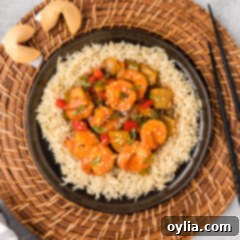 Plate of Sweet and Sour Shrimp served over rice, garnished with green onions and sesame seeds.