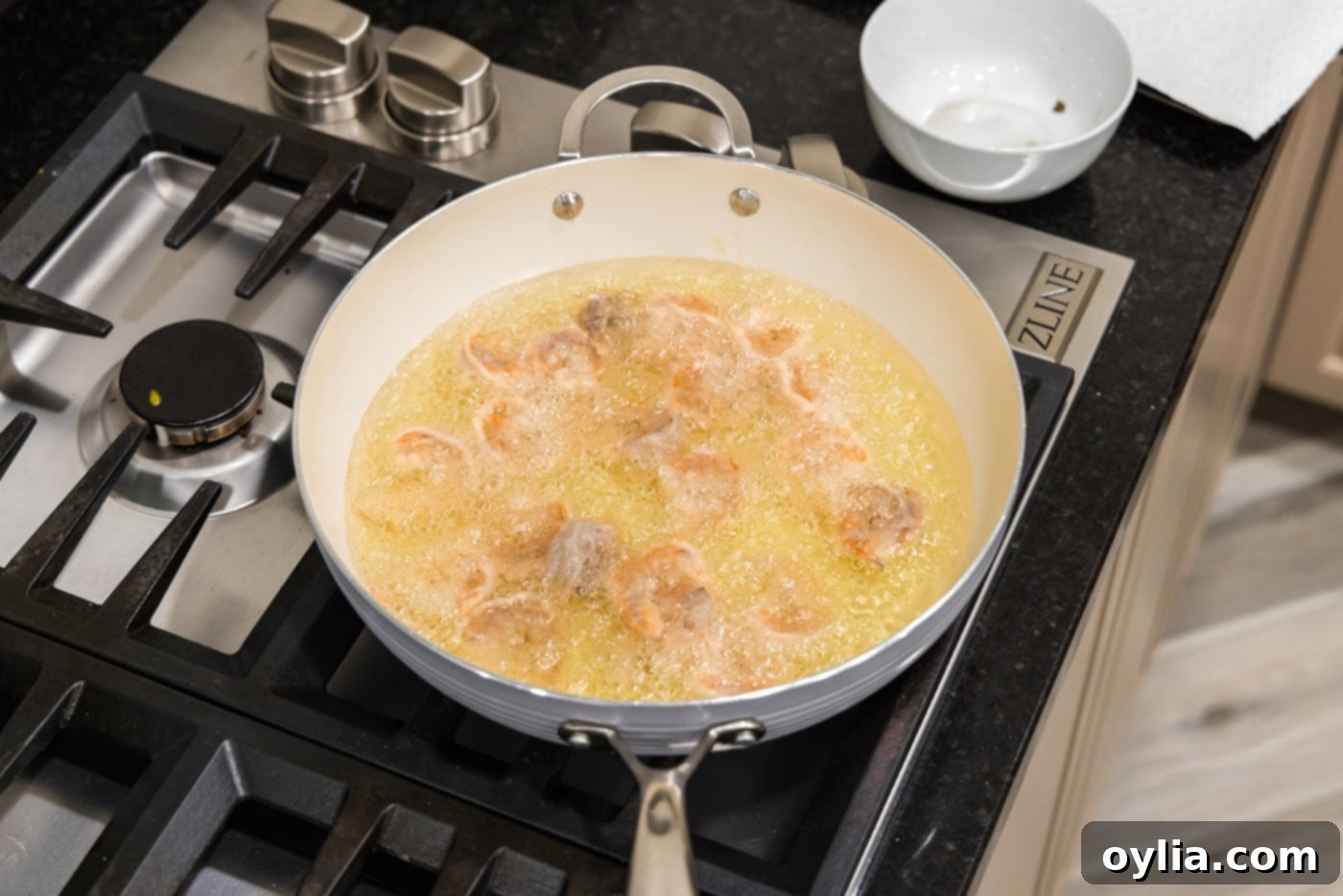 Crispy shrimp deep frying in hot oil in a skillet, turning golden brown.