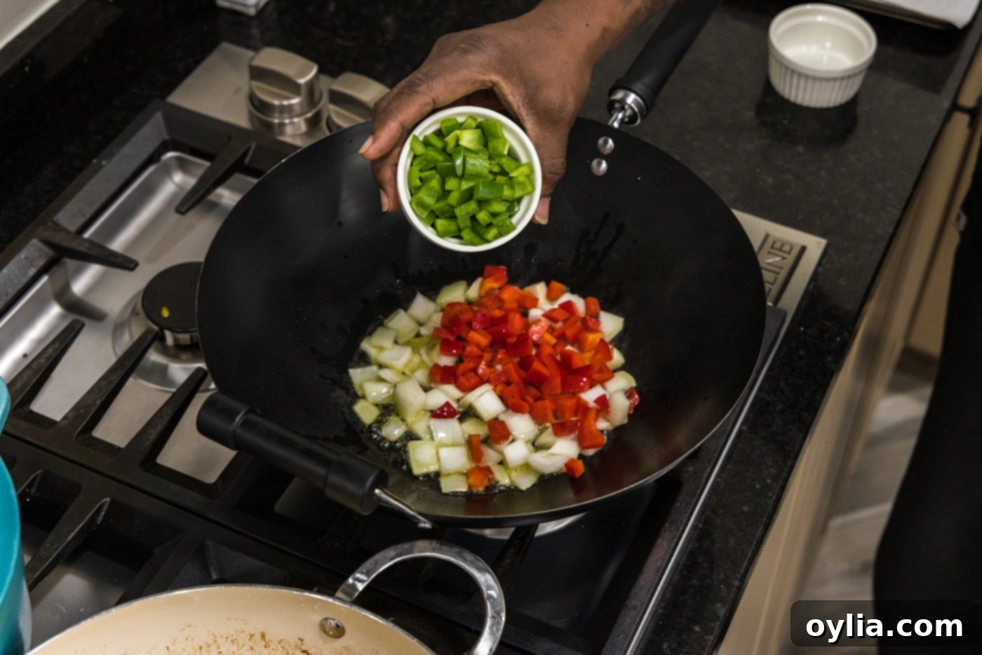 Adding colorful bell peppers and chopped onions to a hot wok, ready for stir-frying.