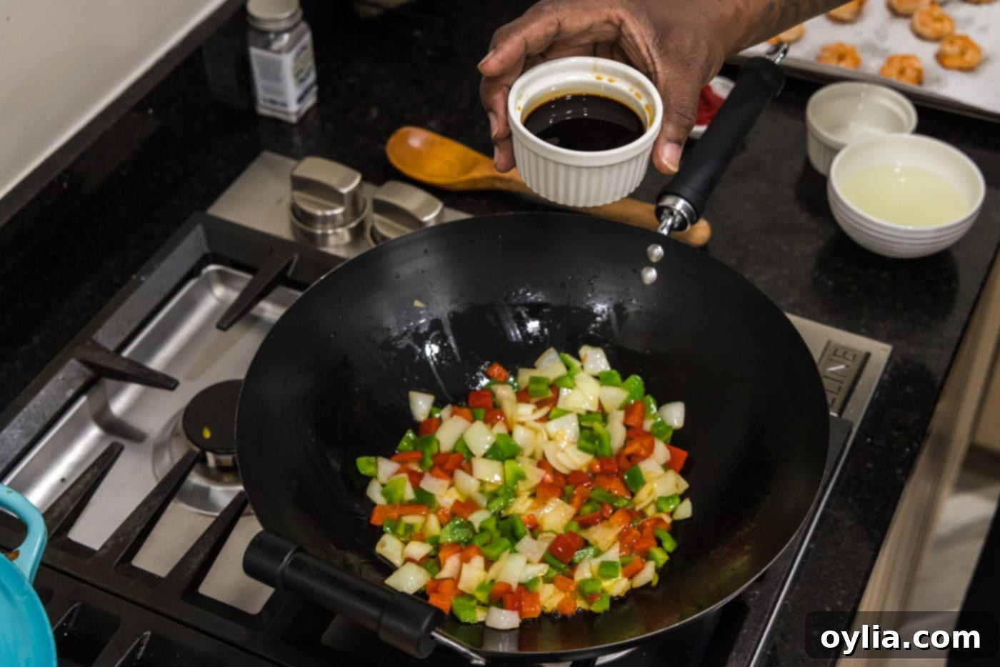 Pouring soy sauce into a skillet with stir-fried vegetables.