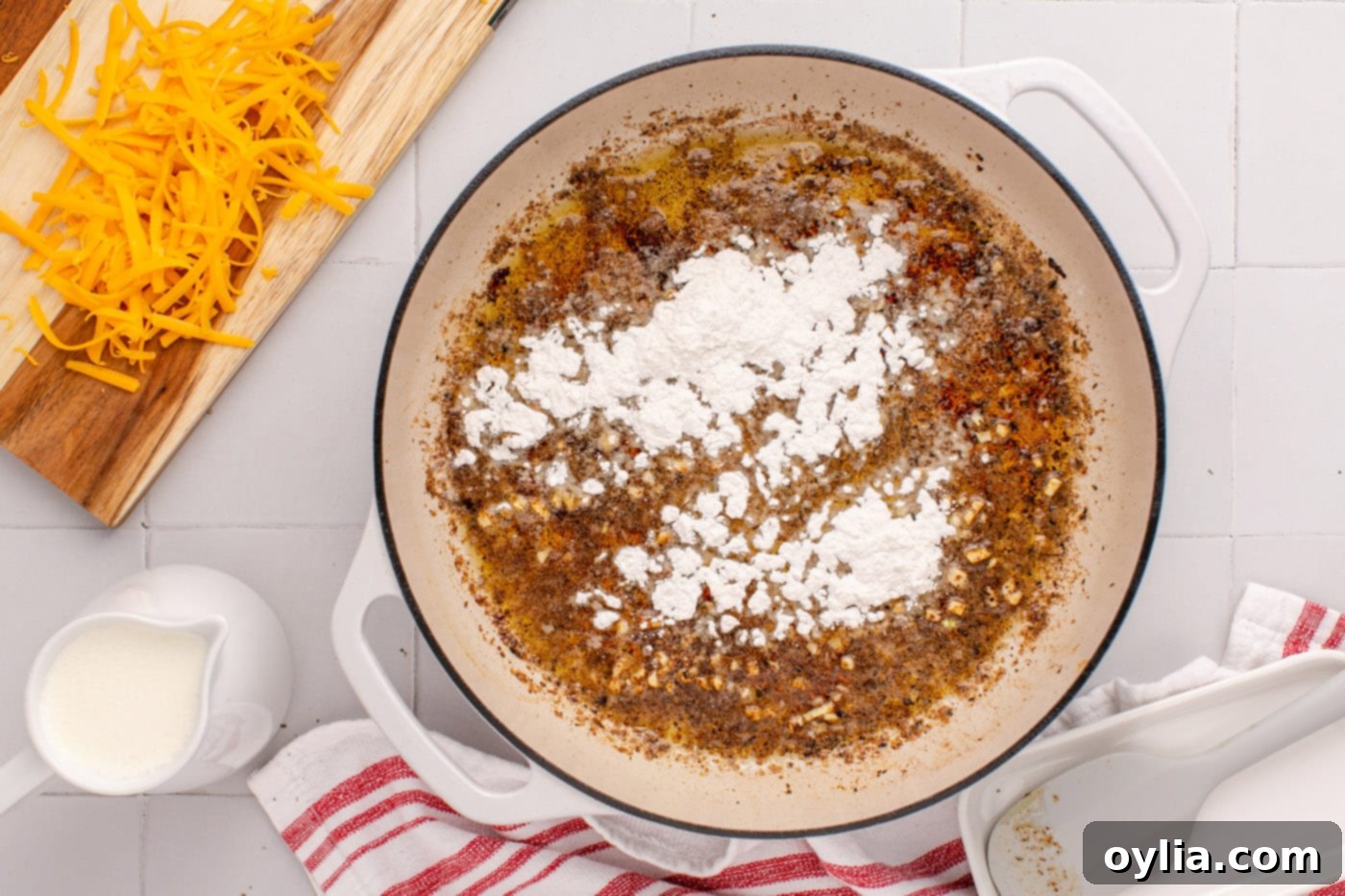 adding flour to skillet with butter and garlic to create a roux
