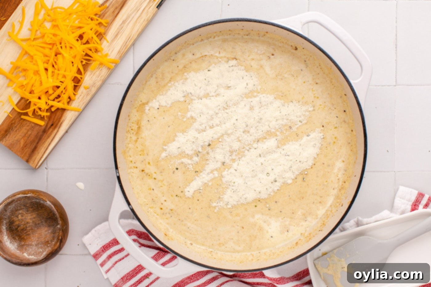 ranch seasoning mix added to cream sauce in skillet, ready to be stirred