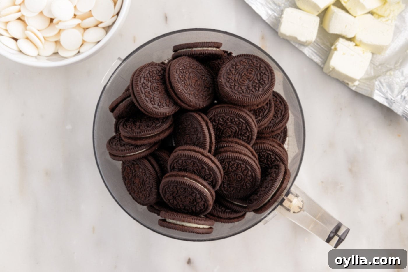 Oreo cookies being pulverized in a food processor to fine crumbs.