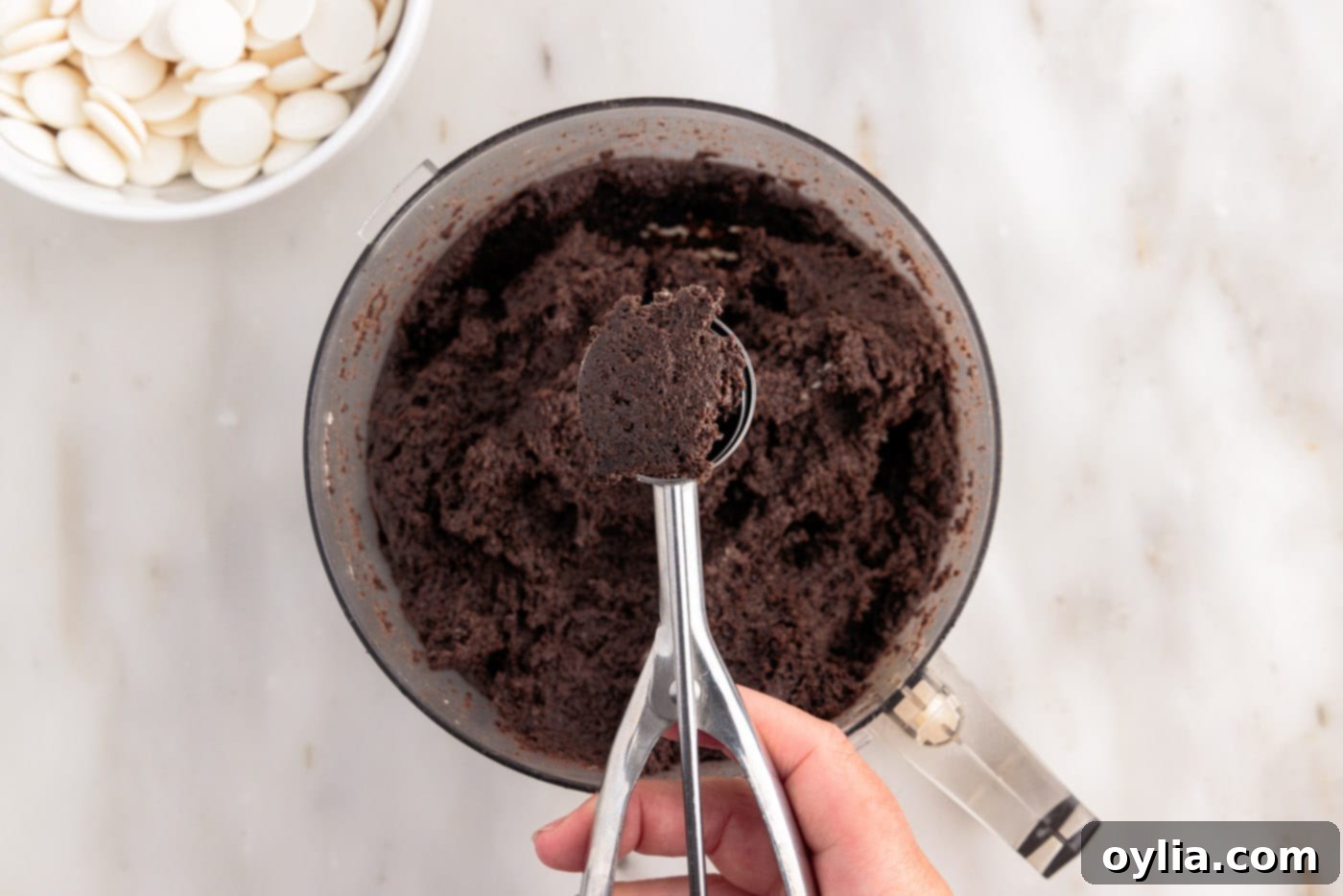 Scooping out the Oreo dough mixture from the food processor.