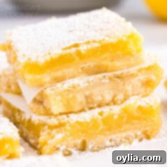 Stack of freshly baked lemon bars, dusted with powdered sugar.
