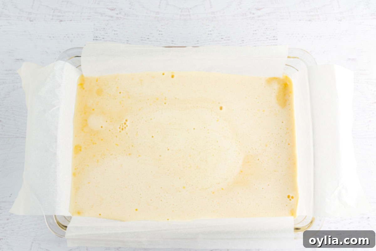 Smooth lemon filling mixture poured over the baked shortbread crust in a baking pan.