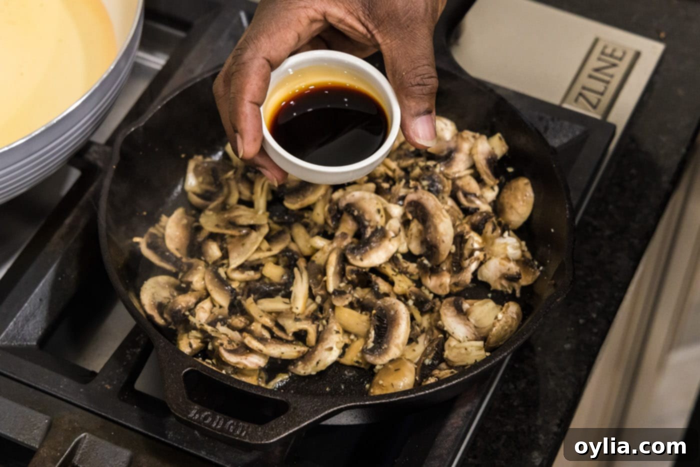 adding soy sauce to mushrooms and garlic in skillet