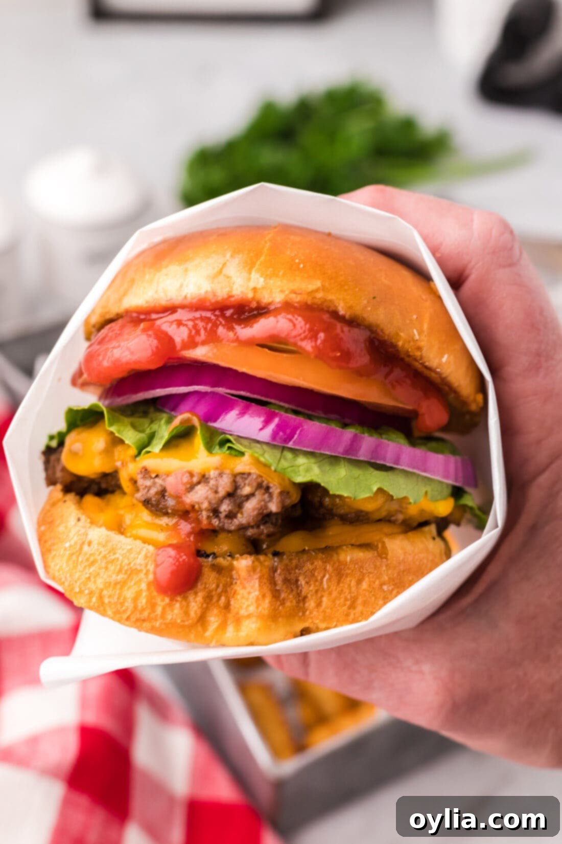Hand holding a Smash Burger wrapped in parchment paper