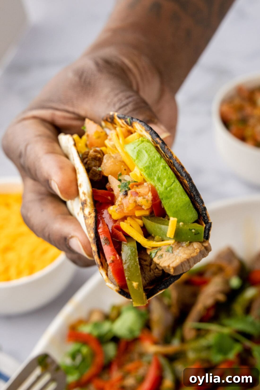 Hand holding Steak Fajitas wrapped in a tortilla