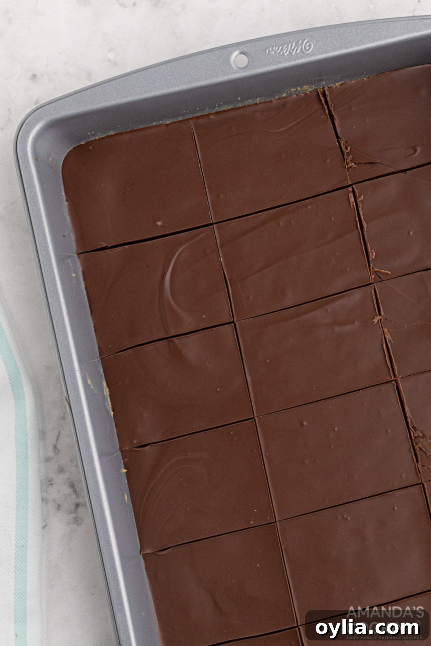 No-bake peanut butter bars with chocolate topping, set and ready to be cut into individual servings in a baking pan.