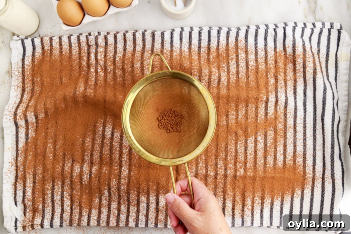 sifting cocoa powder over a clean tea towel on a counter