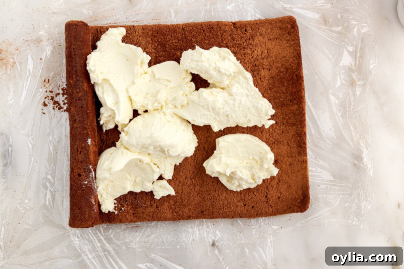 buttercream frosting spread over a chocolate swiss log cake