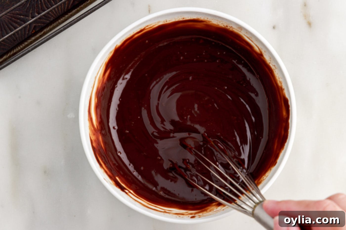 smooth chocolate ganache in a bowl with a whisk