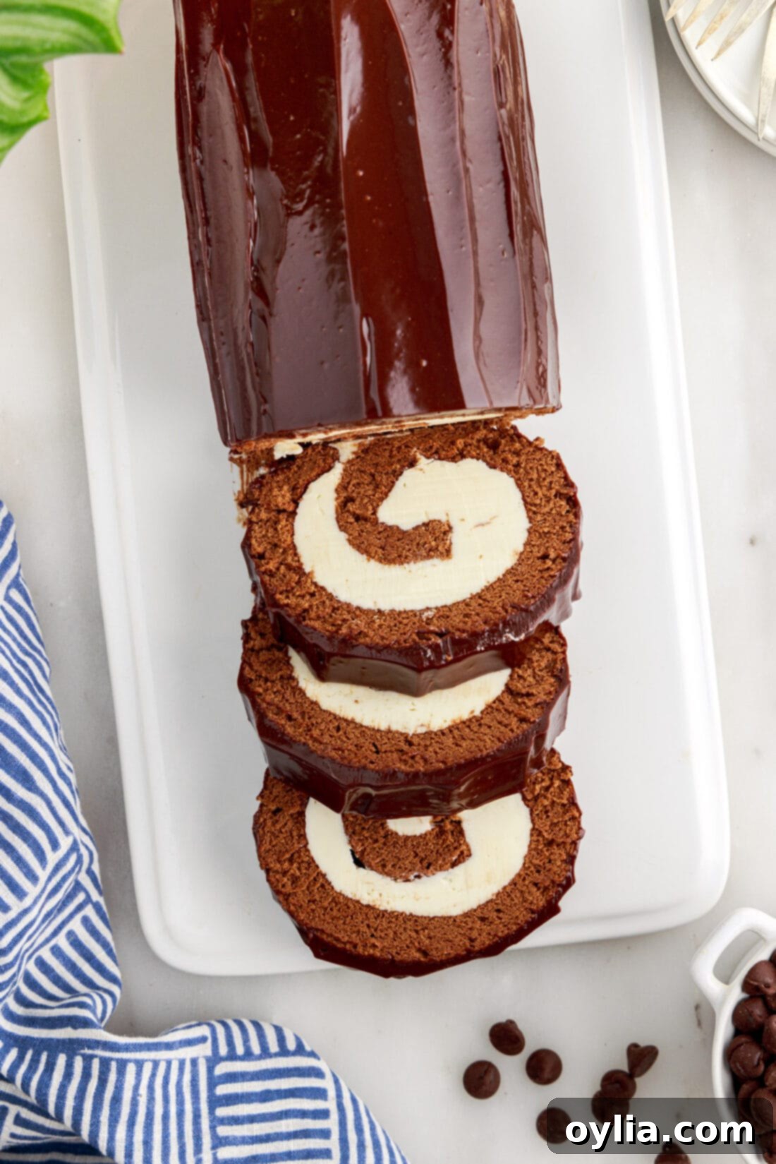 Decadent Chocolate Swirl 28 A beautifully presented Chocolate Swiss Roll with three slices on a white platter, ready to be served.