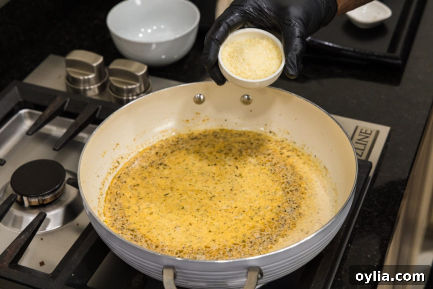 adding parmesan to cream sauce on the stovetop