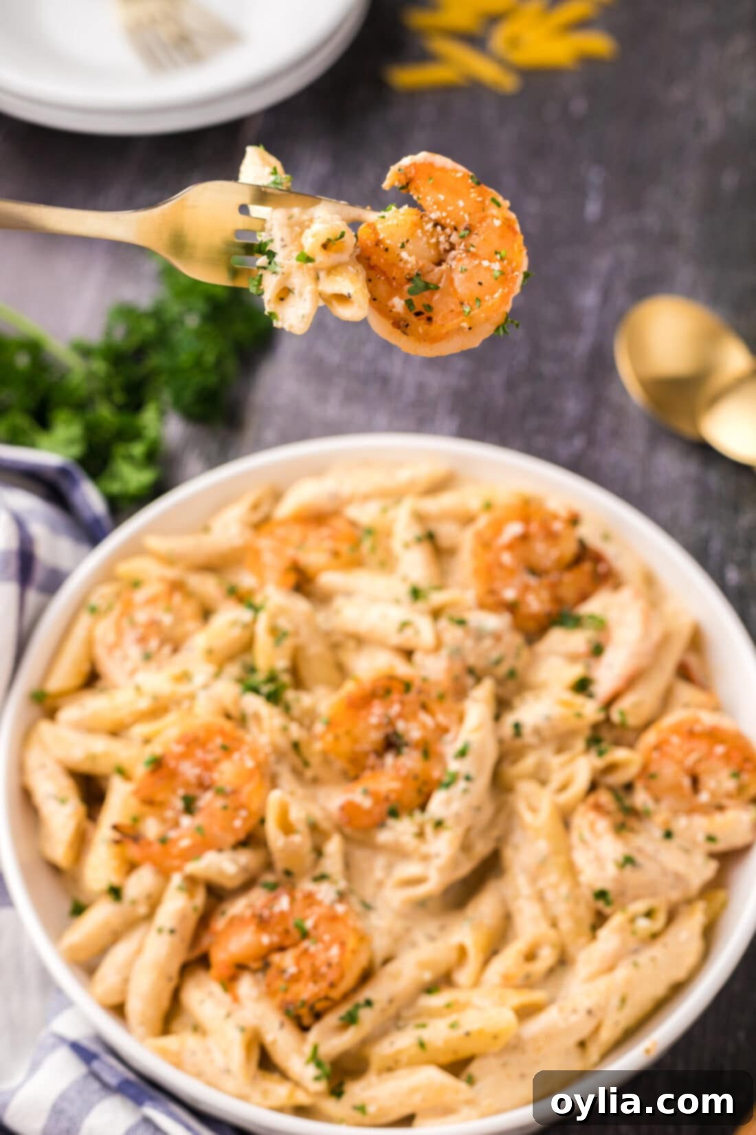 Cajun Shrimp Pasta on a fork held above a bowl of Cajun Shrimp Pasta