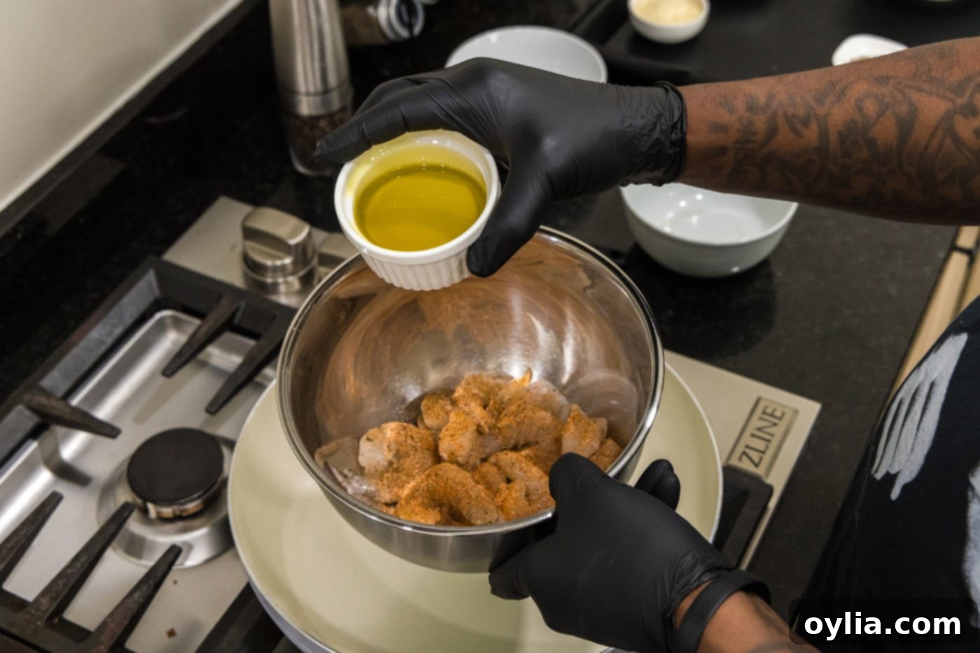 adding olive oil to seasoning shrimp in a bowl