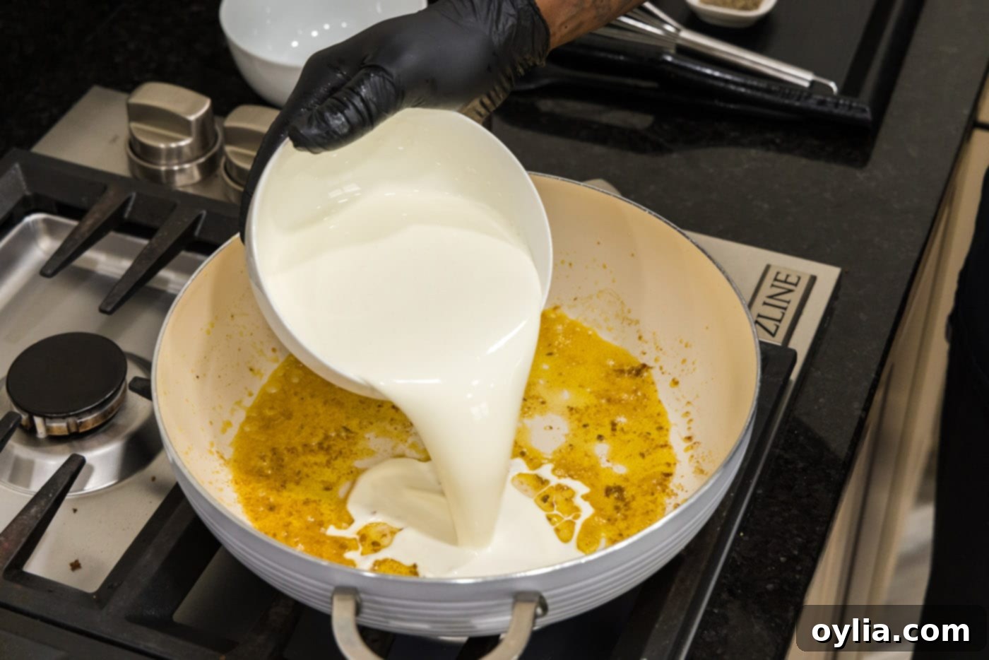 pouring heavy whipping cream into skillet with shrimp drippings
